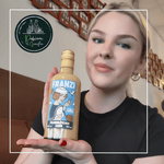 Laden Sie das Bild in den Galerie-Viewer, Eine junge blonde Frau mit einer Flasche Franzi Franzbrötchenlikör
