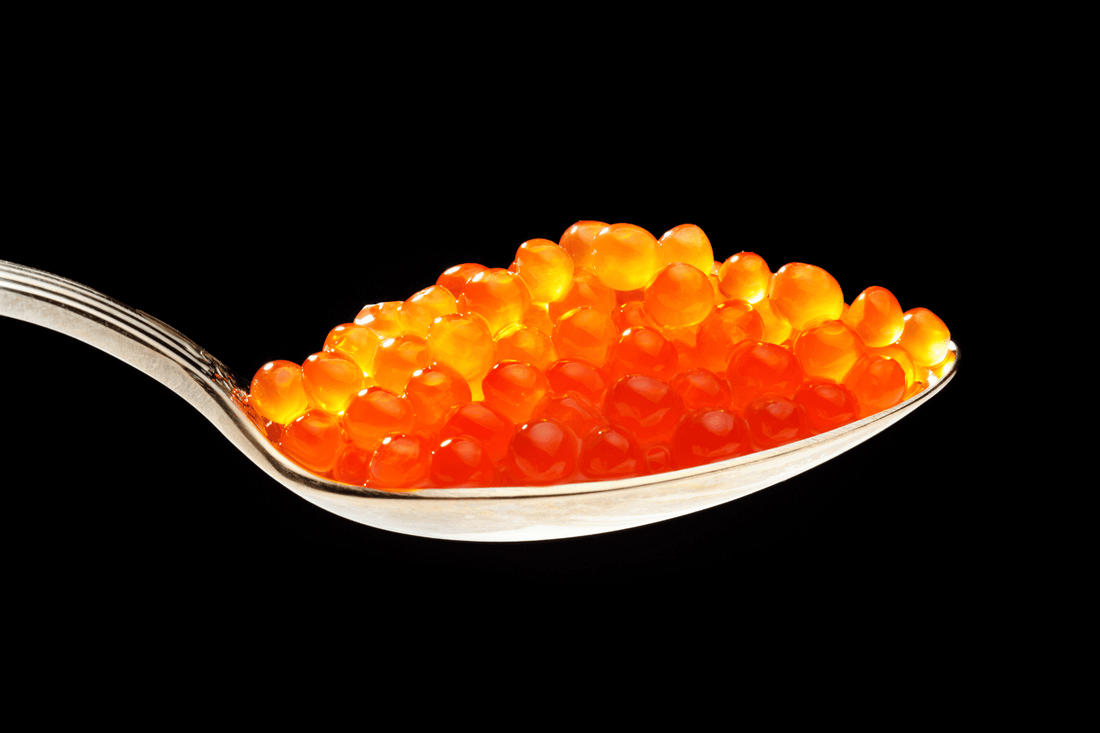 Ein Löffel mit rot leuchtendem Kaviar