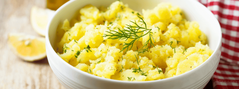 Bester Essig für Kartoffelsalat in einer Schüssel mit Dill und Zitronenscheiben auf einem Holzuntergrund.