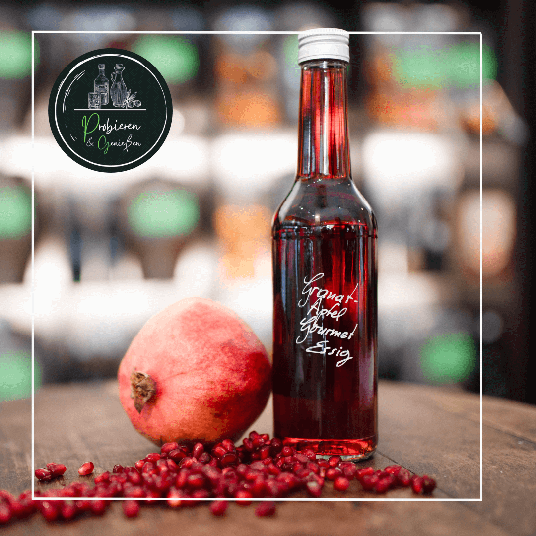 Eine Flasche roter Granatapfelessig neben einem reifen Granatapfel und Granatapfel Kernen in Mannheim