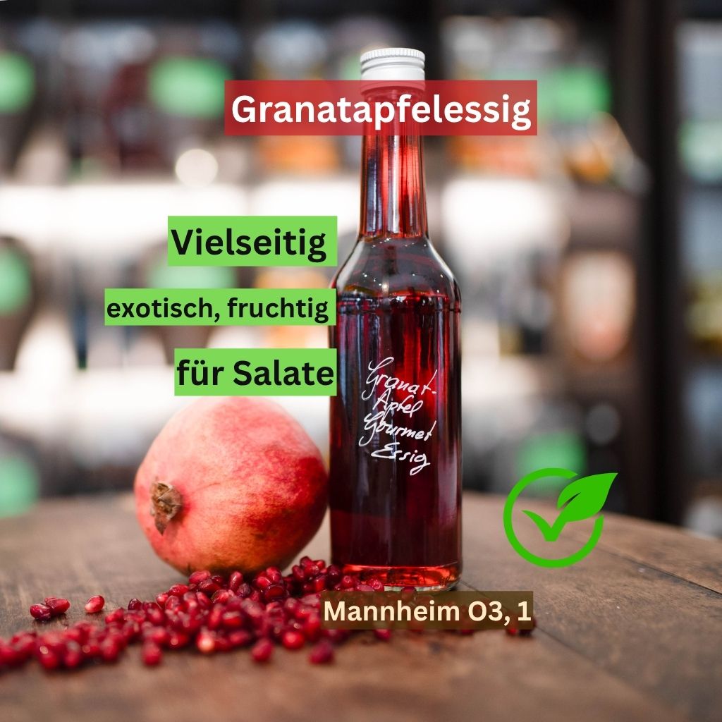 Eine Flasche hochwertiger Granatapfelessig auf einem Holztisch neben einem frischen Granatapfel und Kernen. Text-Einblendungen: „Granatapfelessig kaufen Mannheim O3, 1“ sowie „vielseitig, exotisch, fruchtig für Salate“ Veganer Granatapfelsssig für Salatdressings online.