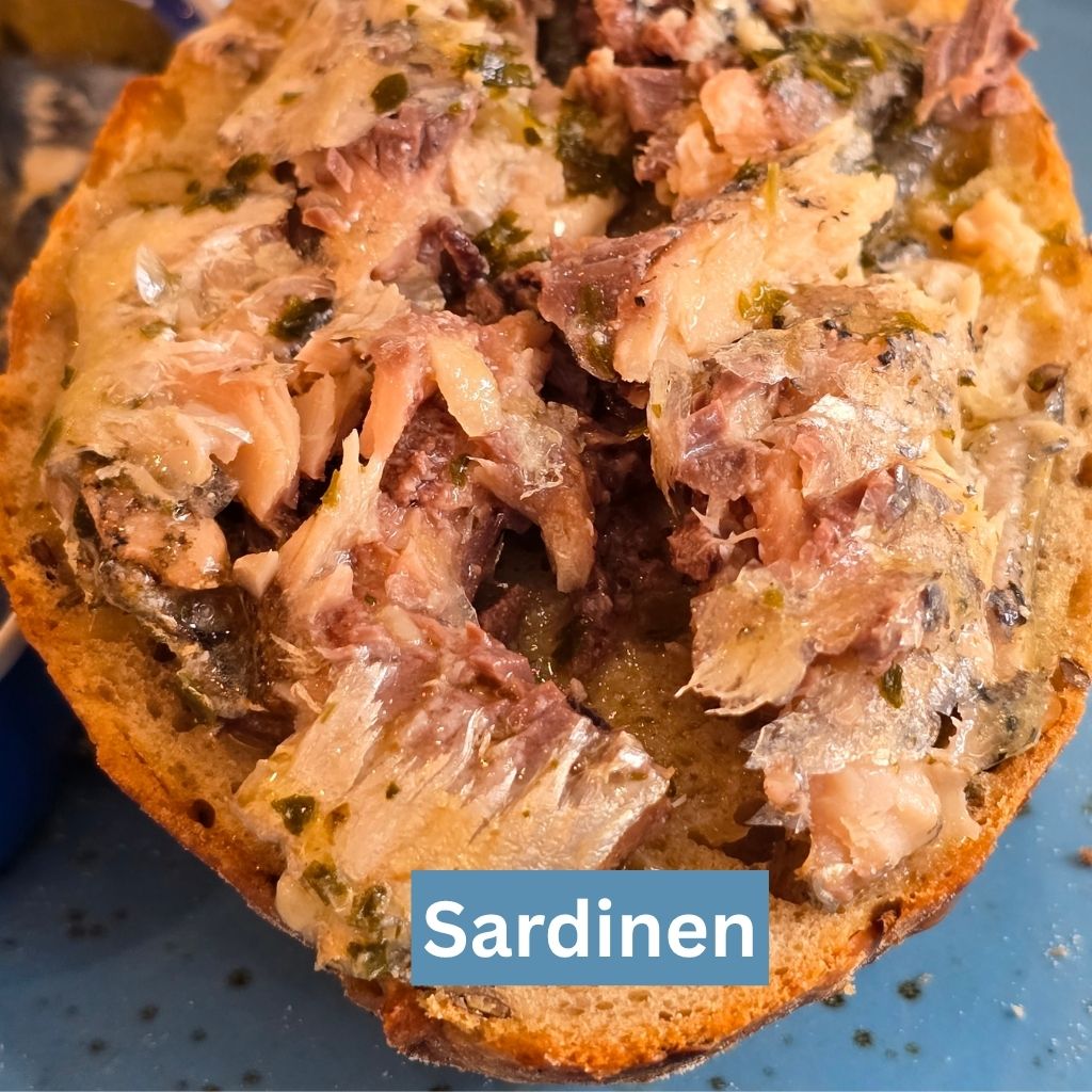 Zart zubereitete französische Sardine mit Kräuter-Olivenöl auf einer knusprigen, gerösteten Brotscheibe, serviert bei Feinkost Probieren & Genießen in Mannheim.