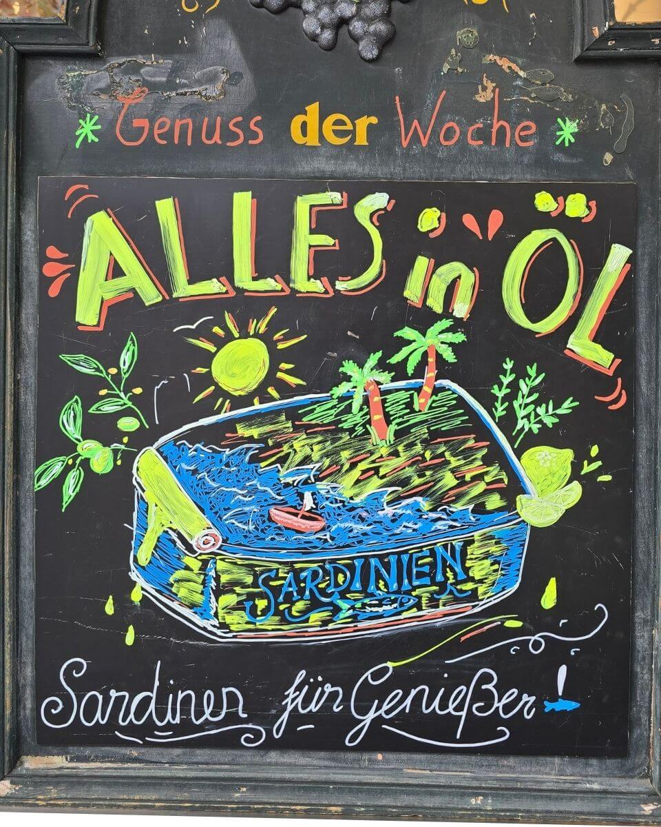 Kreidetafel mit Zeichnung einer Sardinen Konserver: ALLES IN ÖL