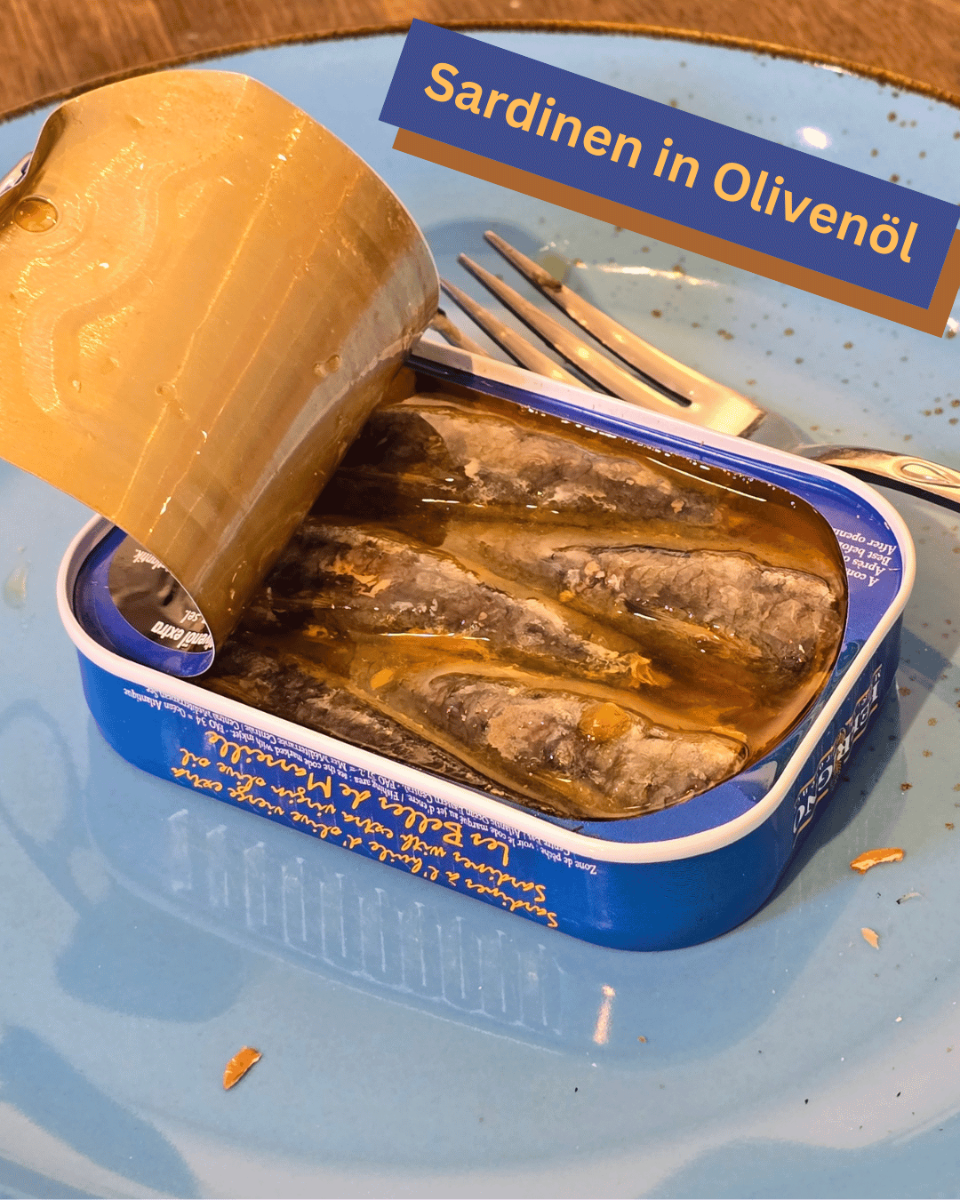Servierfertig angerichtet: Geöffnete Dose Ferrigno Sardinen in extra nativem Olivenöl mit zarten Fischfilets auf einem blauen Teller in Mannheim.